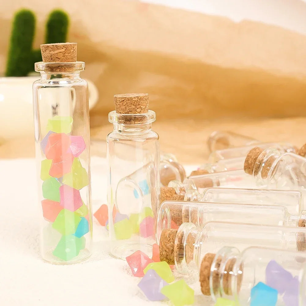 A set of decorative glass bottles filled with colorful glass pieces and cork stoppers