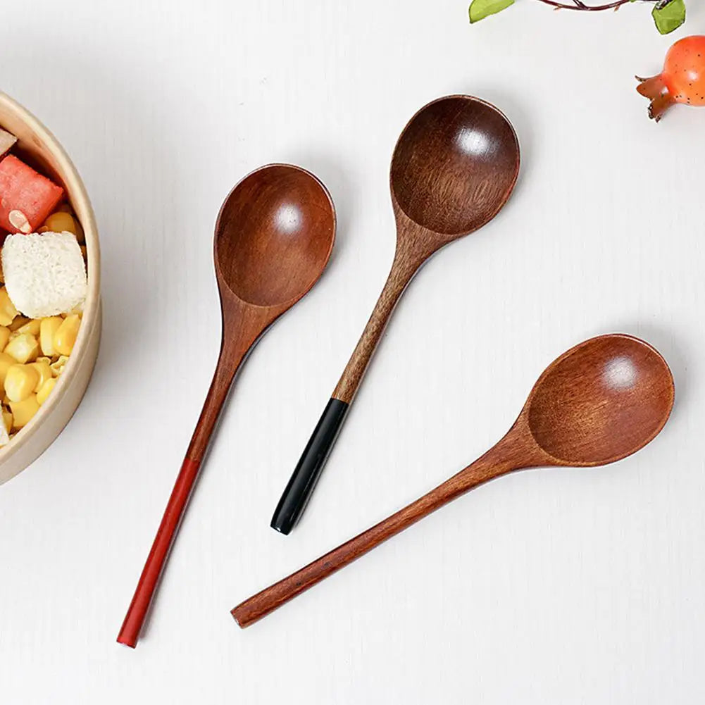 A set of natural wooden cooking spoons resting on a white surface next to some food ingredients.