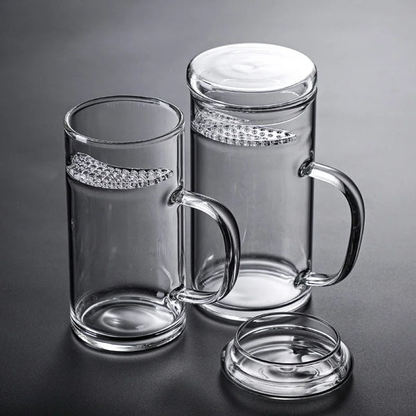 Klare Glas-Tasse mit silberner Sichelfilter auf dunkler Oberfläche.
