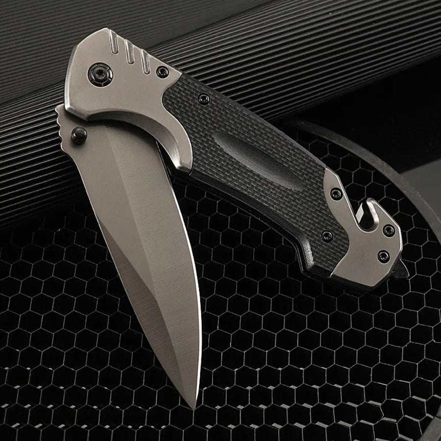A close-up view of a gray heavy duty outdoor folding pocket knife resting on a black textured surface.