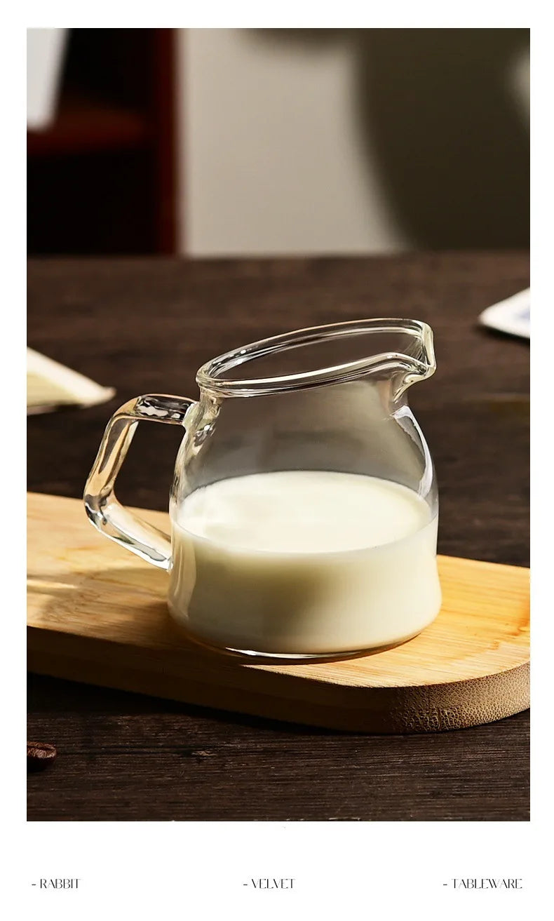 A clear glass pitcher filled with white milk is placed on a wooden cutting board.