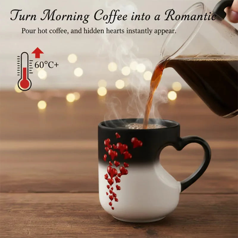 A black mug with a heart design is pouring hot coffee into a white cup, creating steam and a romantic atmosphere.