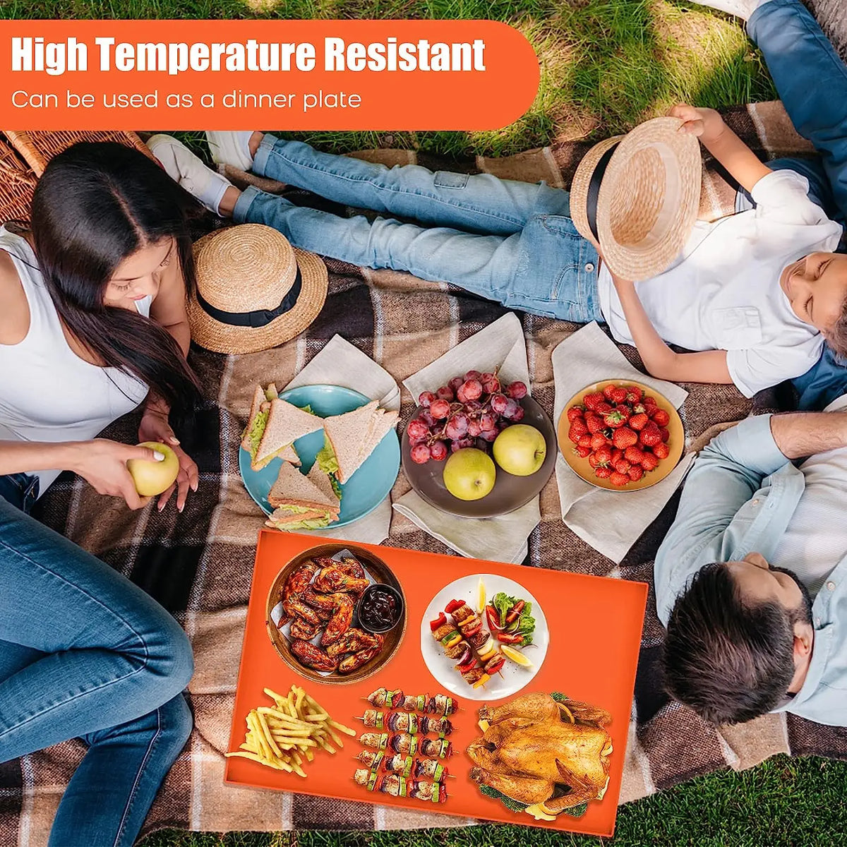 A family enjoying a meal on an orange silicone BBQ baking mat outdoors.