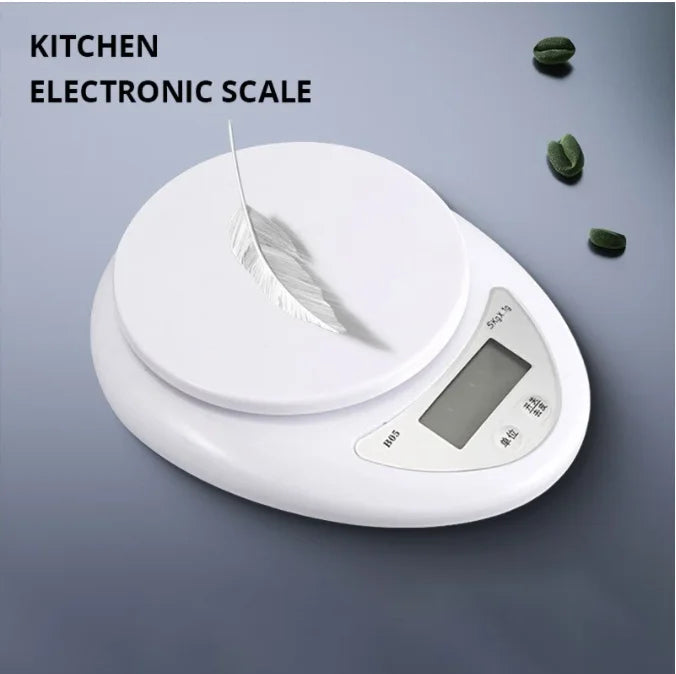 A white electronic kitchen scale with a feather placed on the weighing platform.