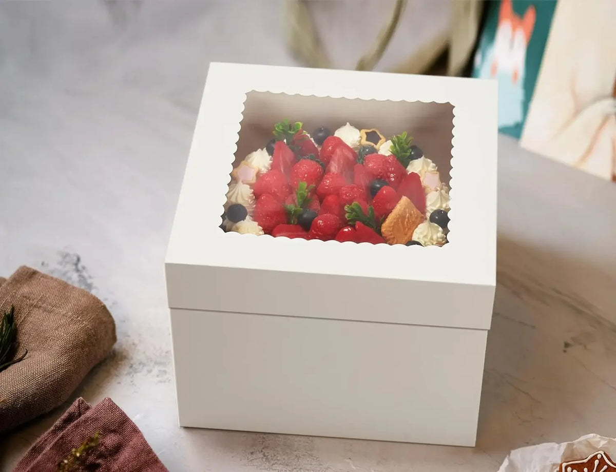 A white square window box filled with fresh strawberries, blueberries, and cream, set on a light surface.