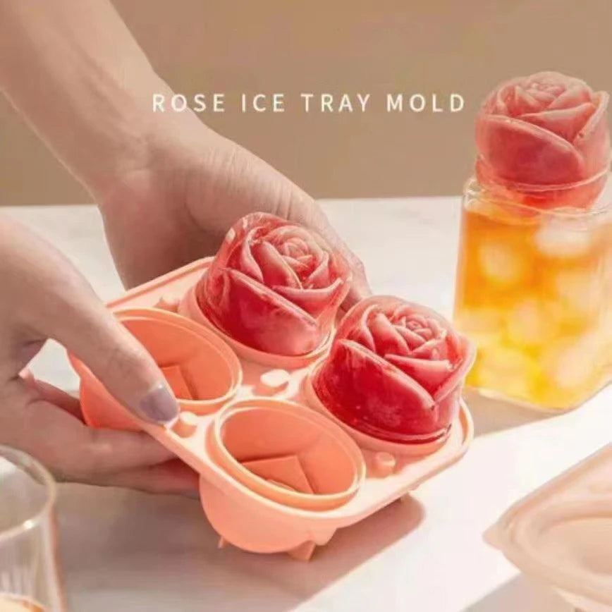 Hands are pressing pink rose ice tray molds into a glass of orange liquid.