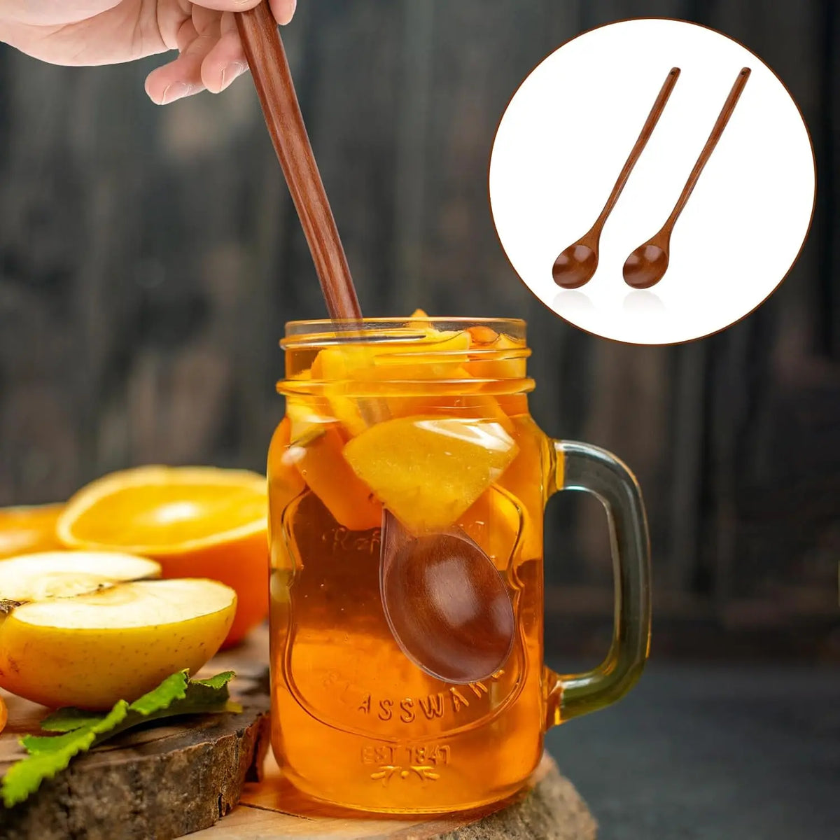 A glass of orange juice with slices, served in a mug, next to a wooden spoon and a set of wooden serving spoons.