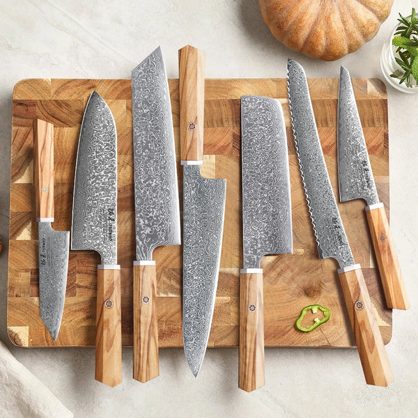 Set von sieben japanischen Küchenmessern aus rostfreiem Damaszinklinge mit Holzgriffen auf einem Holzbrett