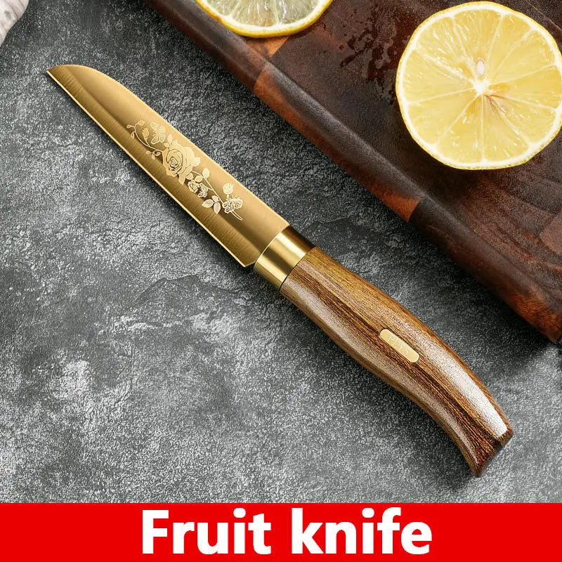 A golden rose stainless steel fruit knife with a wooden handle resting on a dark gray surface next to a slice of lemon.