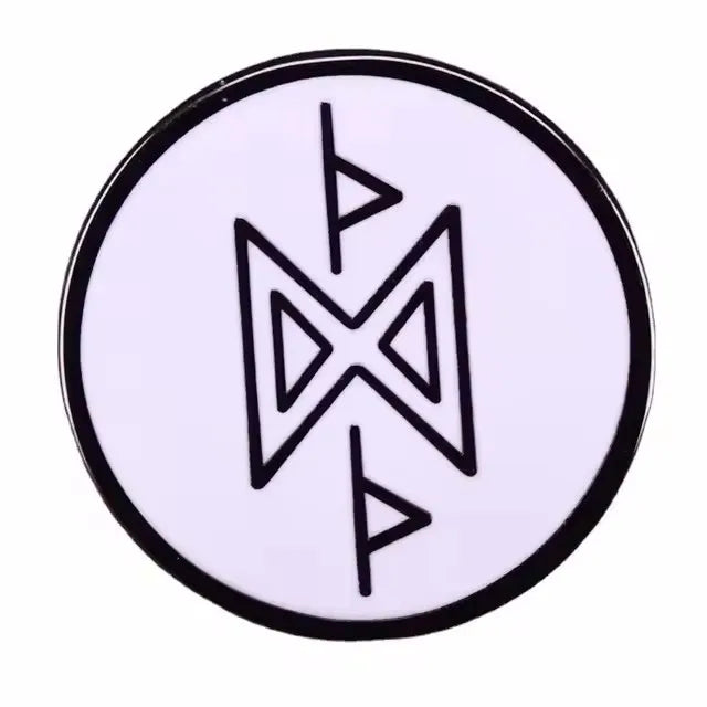 A round enamel pin featuring a stylized geometric design in black on a white background.