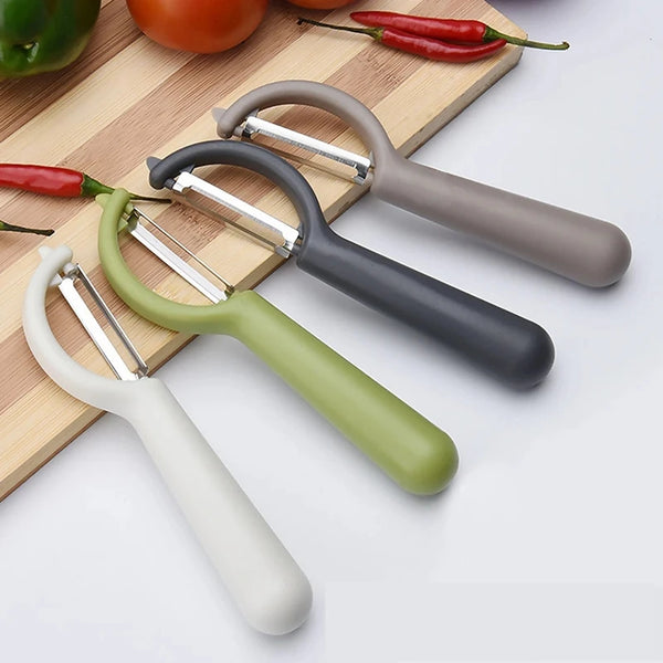 Ein Set aus drei Edelstahl-Gemüsehobel in verschiedenen Farben auf einem Holzbrett mit frischen Chilis