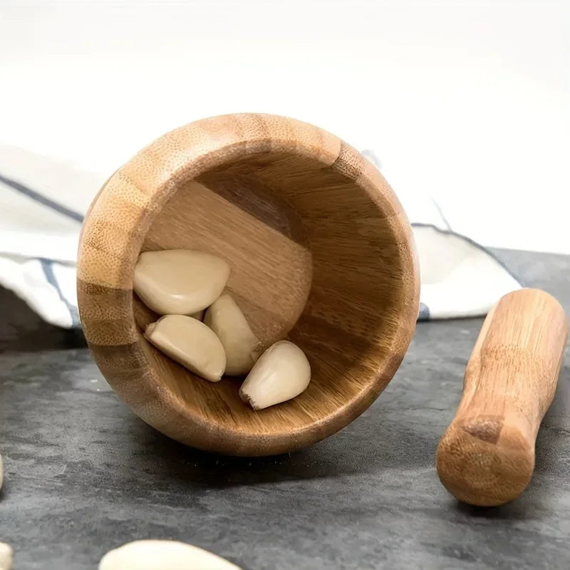 A wooden bamboo mortar and pestle set resting on a dark surface with a white cloth in the background.