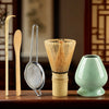 A set of bamboo and metal tools including a whisk, spoon, and a bundle of bamboo straws for tea preparation.