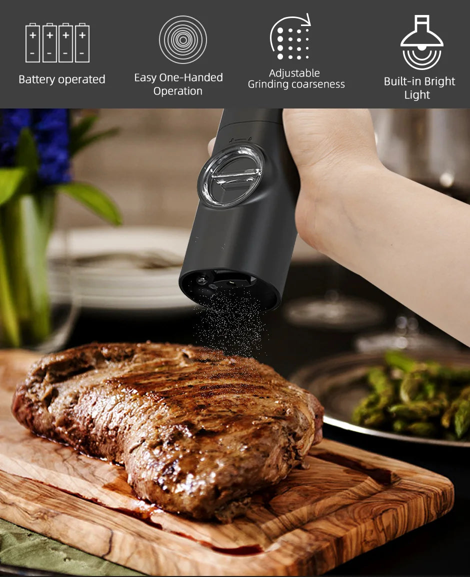 A hand is using a black electric automatic salt and pepper grinder to grind spices over a steak on a wooden cutting board.