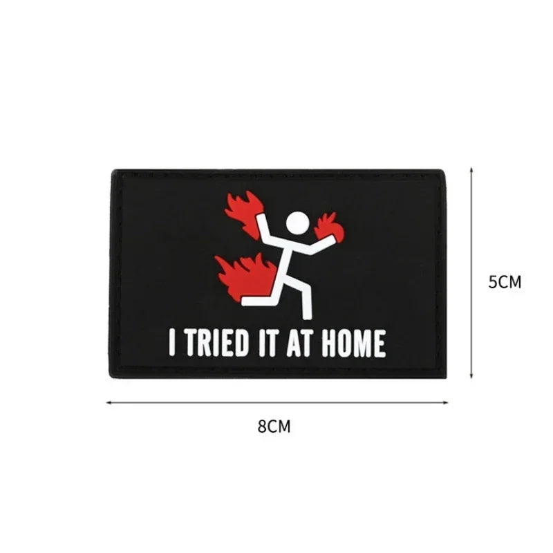 Black rectangular patch featuring a silhouette of a person struggling with flames and the text I TRIED IT AT HOME