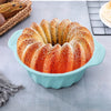 A golden ring of baked croissants in a light blue silicone baking pan with a pastry brush nearby.