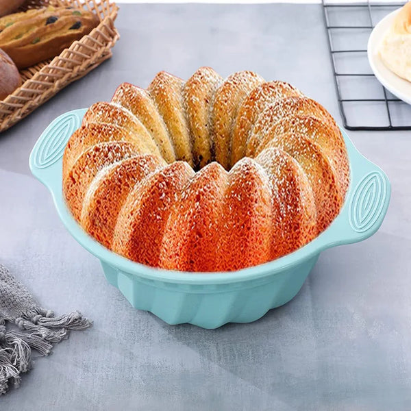 A golden ring of baked croissants in a light blue silicone baking pan with a pastry brush nearby.
