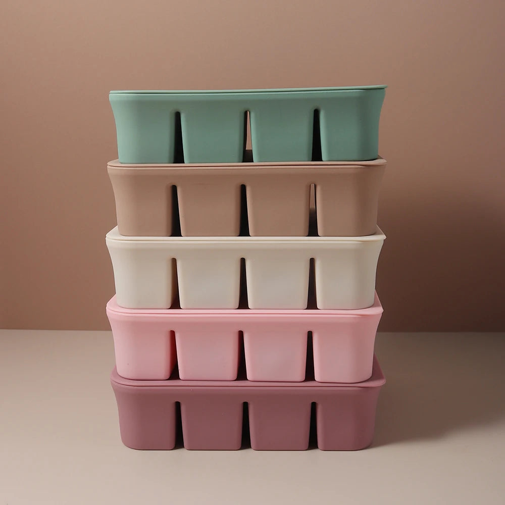 A stack of five silicone food trays in pastel shades of mint green, pink, and white on a neutral background.