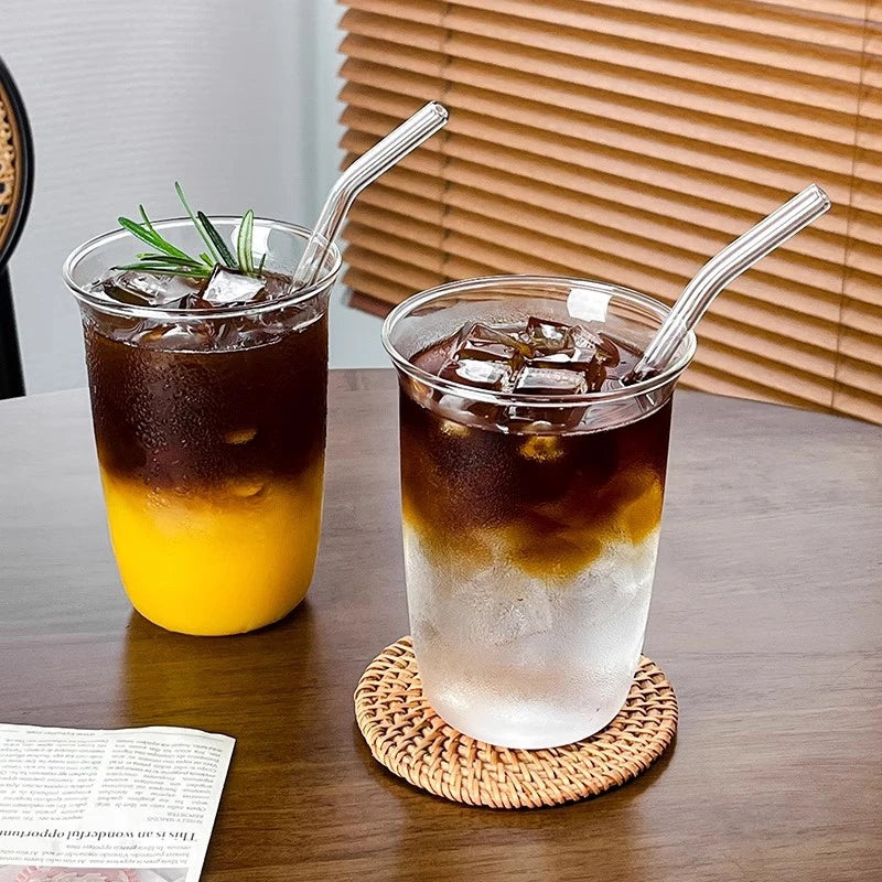A tall glass tumbler filled with iced tea, served on a woven coaster.