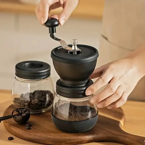 Eine Hand bedient einen manuellen Keramik-Kaffeemühle, die Mahlwerk und gemahlenen Kaffee auf einem Holzbrett zeigt.