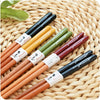 A set of five pairs of natural bamboo chopsticks with non-slip grips arranged on a woven mat.