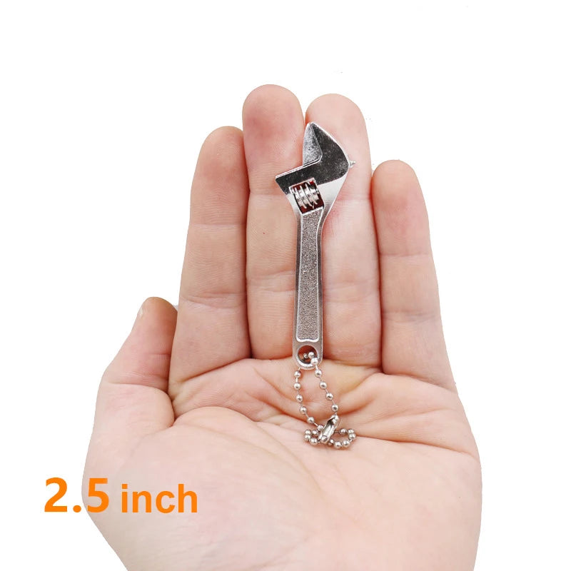 A hand holds a silver compact mini adjustable spanner wrench with a chain loop.