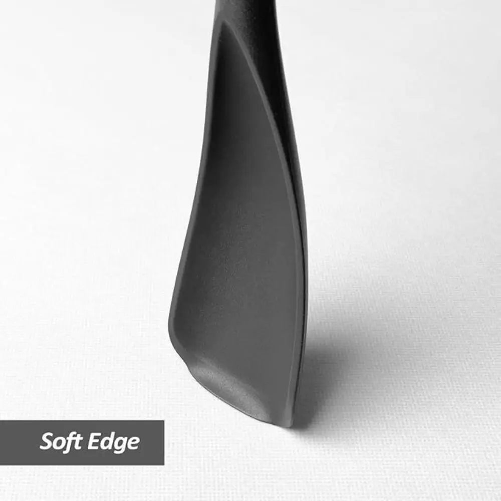 A close-up view of a black heat resistant silicone stirring spoon with a soft edge.