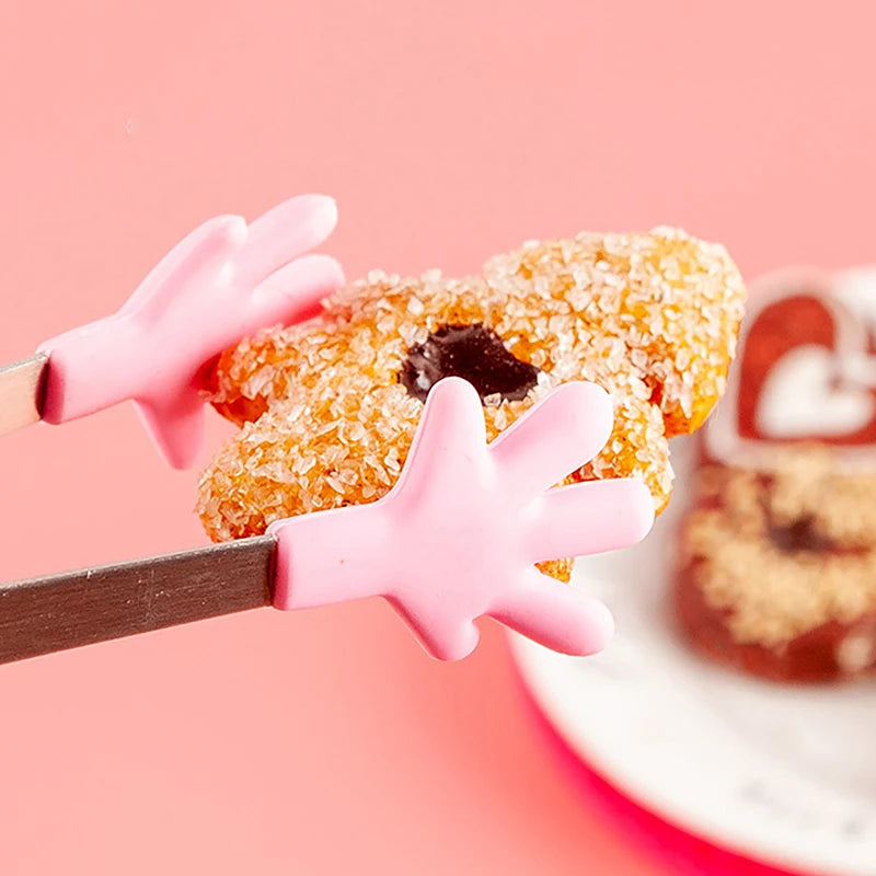 Pink silicone food tongs holding a glazed pastry on a white plate.