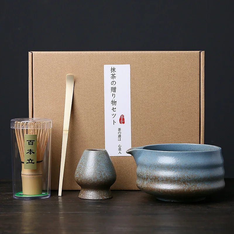 A set of Japanese matcha whisks and a ceramic bowl are displayed in front of a brown cardboard box.