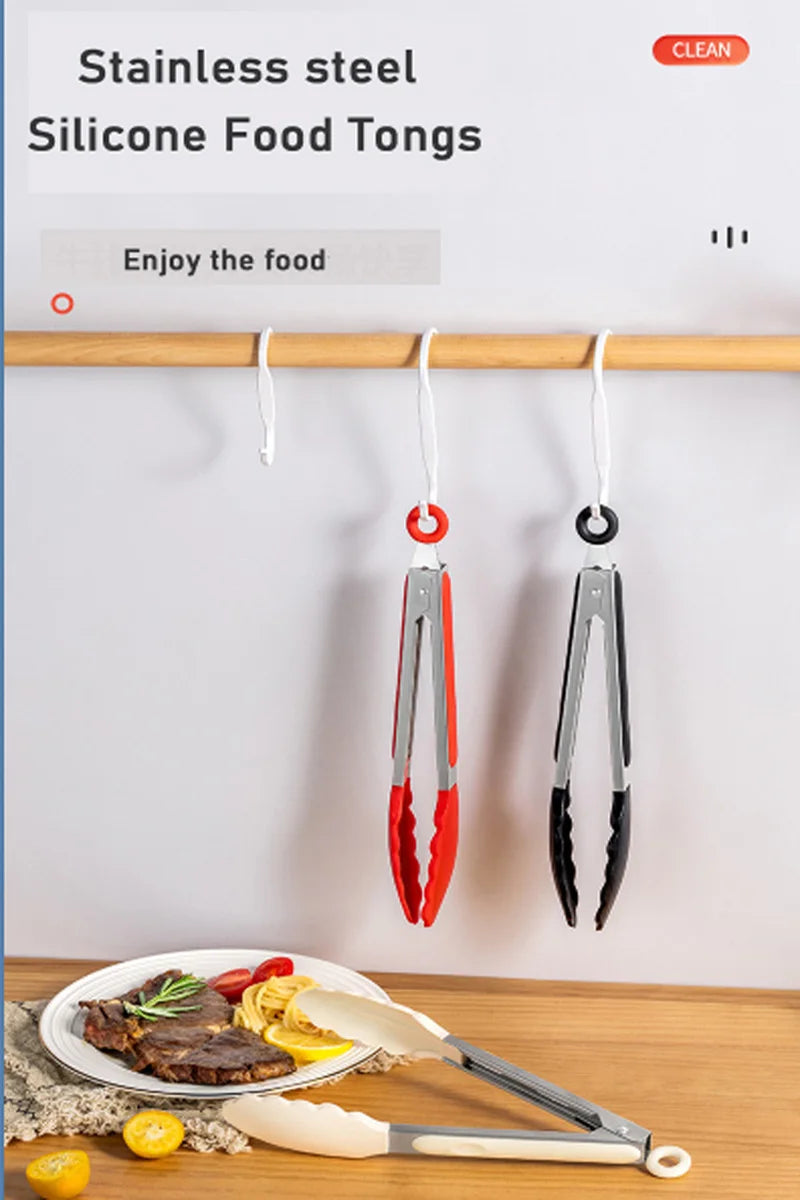 Stainless steel silicone food tongs hanging on a wooden rack next to cooked meat and citrus fruit.