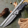 A heavy duty outdoor folding pocket knife with a silver blade and black handle rests on a green surface next to a measuring r