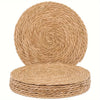 A stack of round, woven natural rattan placemats in a light tan color.
