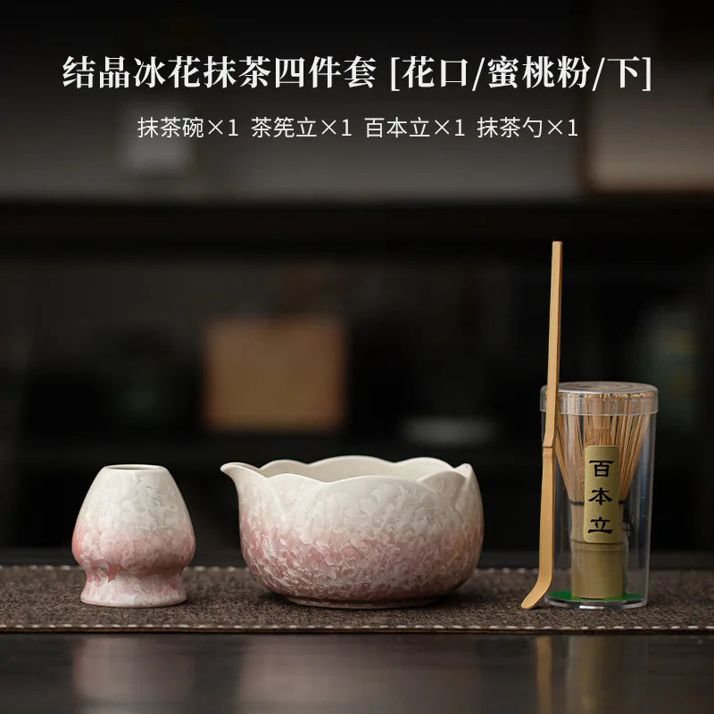 Un juego de cuatro batidores de matcha de cerámica y una taza de té sobre una superficie oscura.