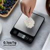 A hand is placing a pile of white powder onto a digital kitchen scale for precise weighing.