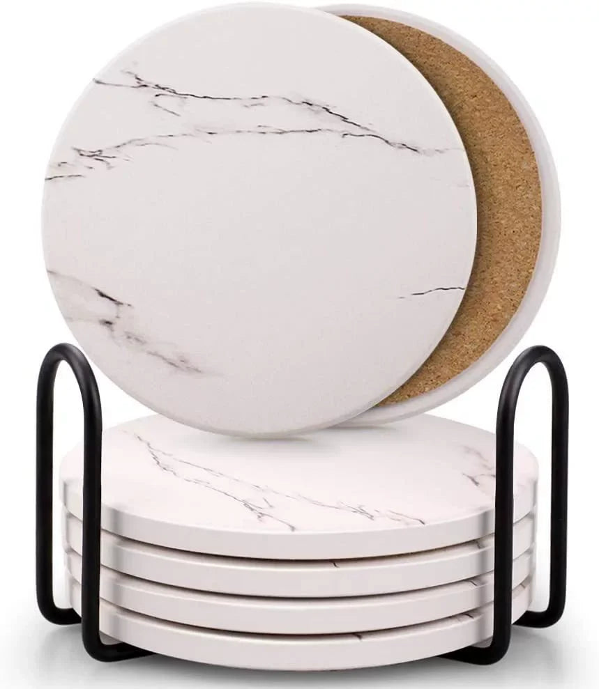 A stack of six white marble style acrylic coasters with cork backing in a black holder.