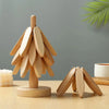 A set of natural wood insulation coasters shaped like pine branches resting on a light wooden surface.