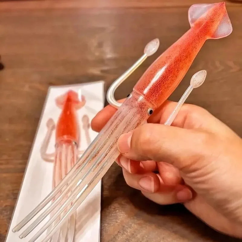 A hand holds a red squid cuttlefish themed fork and a small piece of the same product on a white plate.