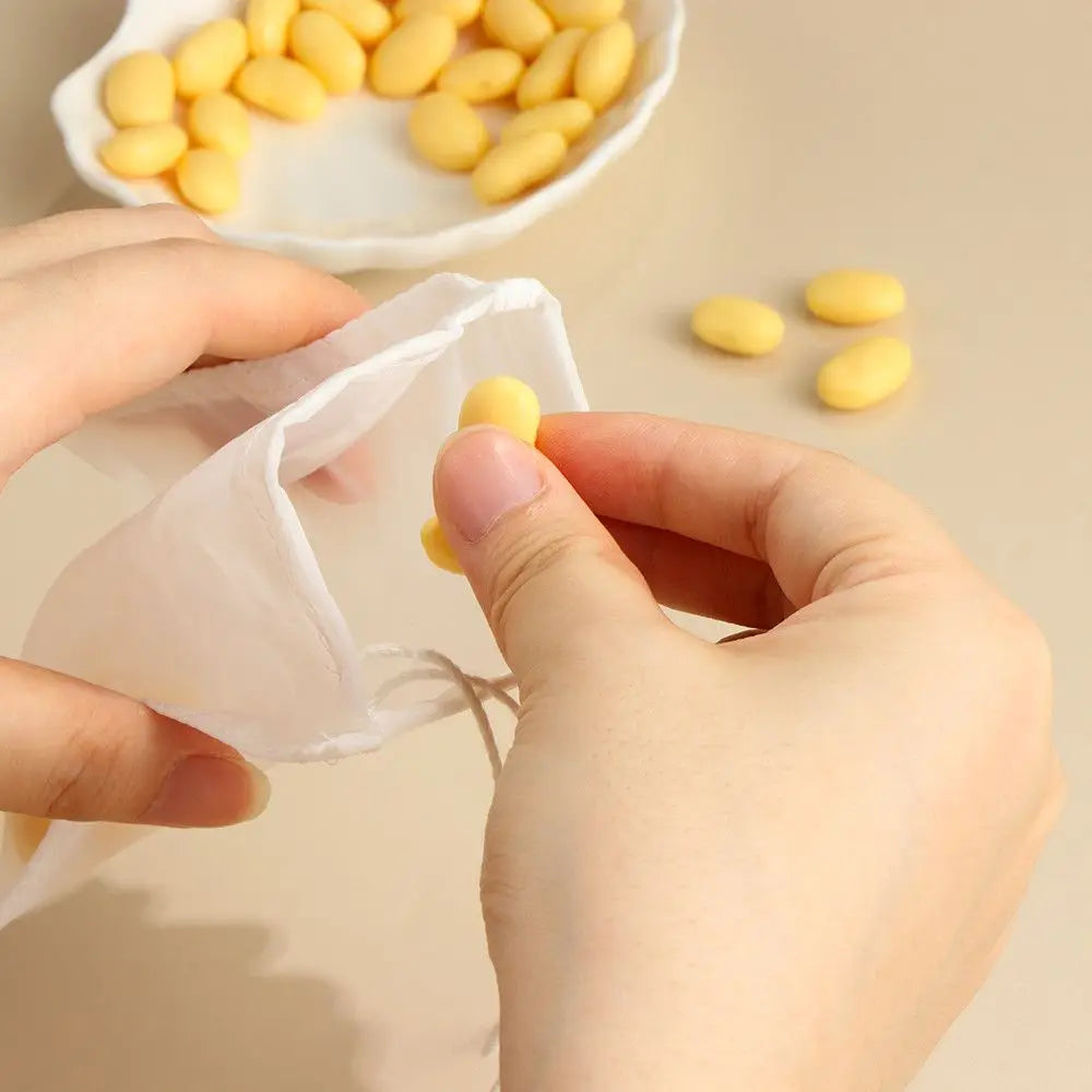 A hand is using a piece of white cloth to pick up yellow food items from a white strainer or colander.