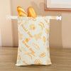 Bolsas de pan de cera de abeja reutilizables con fondo amarillo claro y ilustraciones de trigo, abejas y panes.