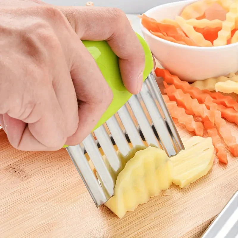 A hand is using a green plastic tool to cut yellow fruit pieces on a wooden board.