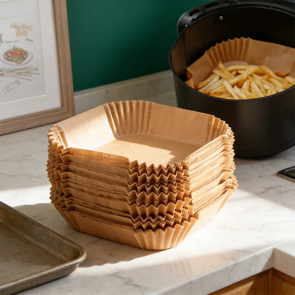 Eine Stapel wiederverwendbare antihaftbeschichtete Backmatten für Airfryer auf einer Marmor-Arbeitsplatte neben einem schwarz