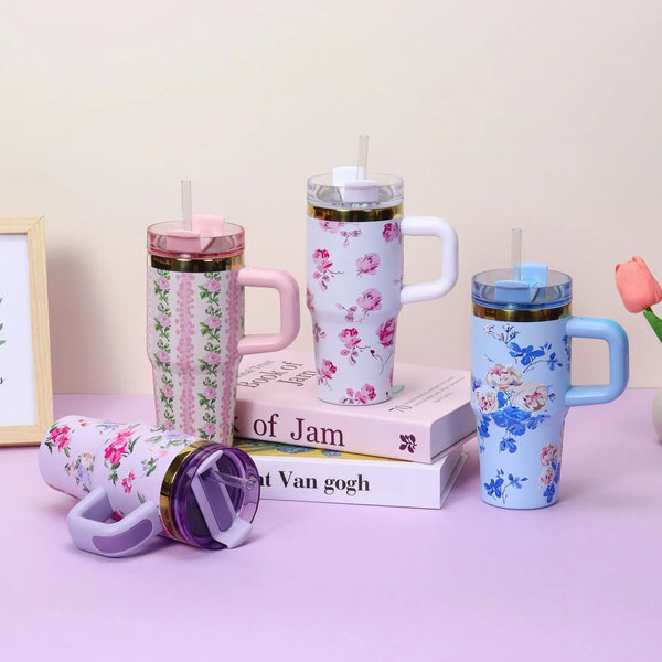 A collection of pink and blue floral stainless steel insulated travel tumblers with lids displayed on a light purple surface.