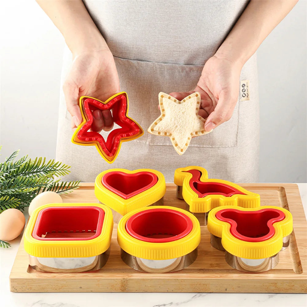 A set of geometric sandwich cutters in red and yellow plastic are being held by hands over a wooden cutting board.