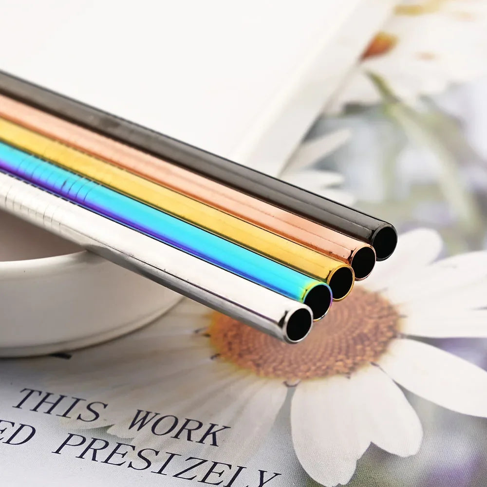 A close-up of a reusable metal straw set with various colored stainless steel drinking pipes resting on a white surface.