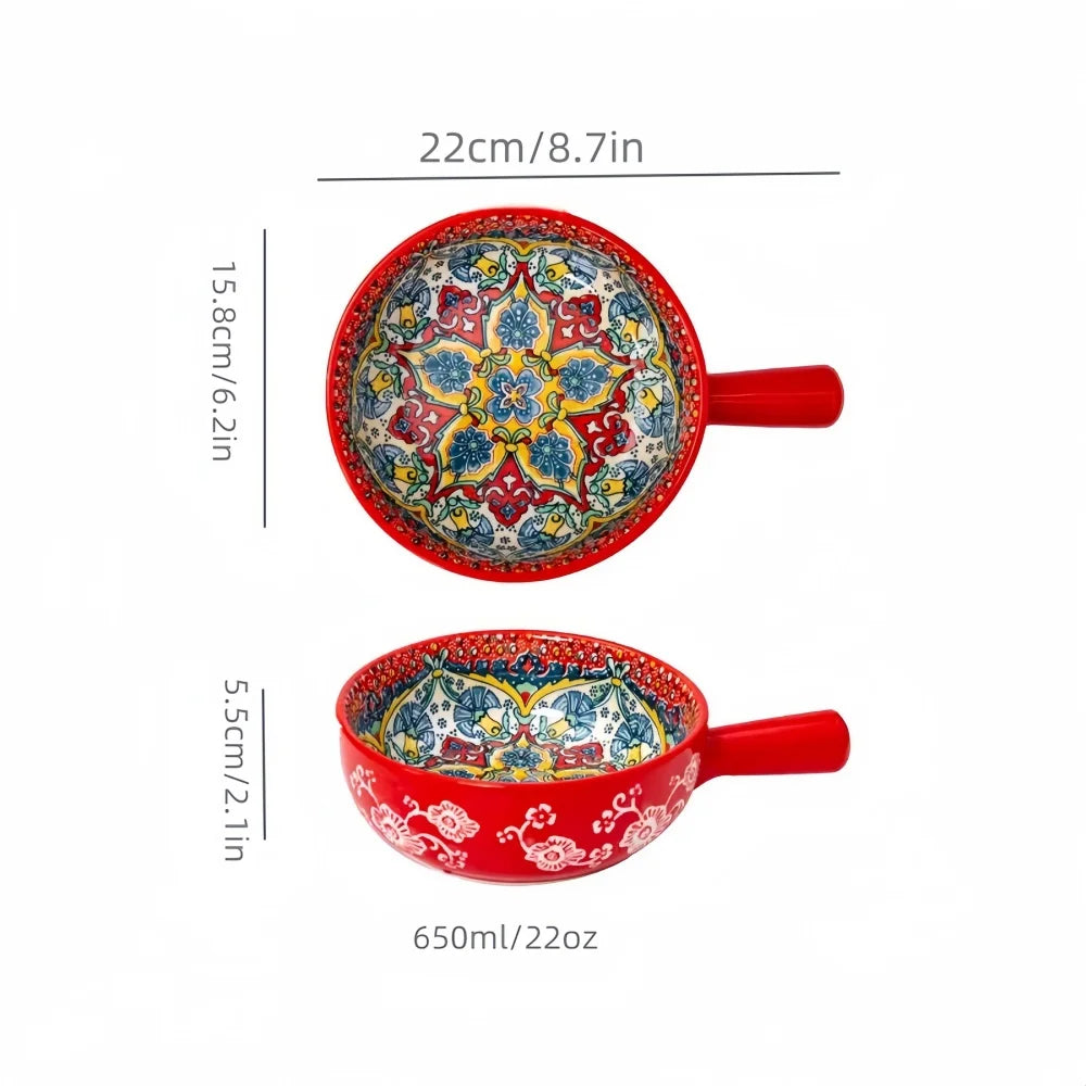 A red ceramic salad bowl with a handle featuring intricate blue and white hand-painted floral designs.