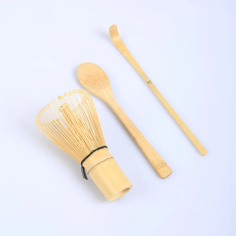 A traditional bamboo and ceramic matcha tea set featuring a whisk and a bamboo scoop on a white background.