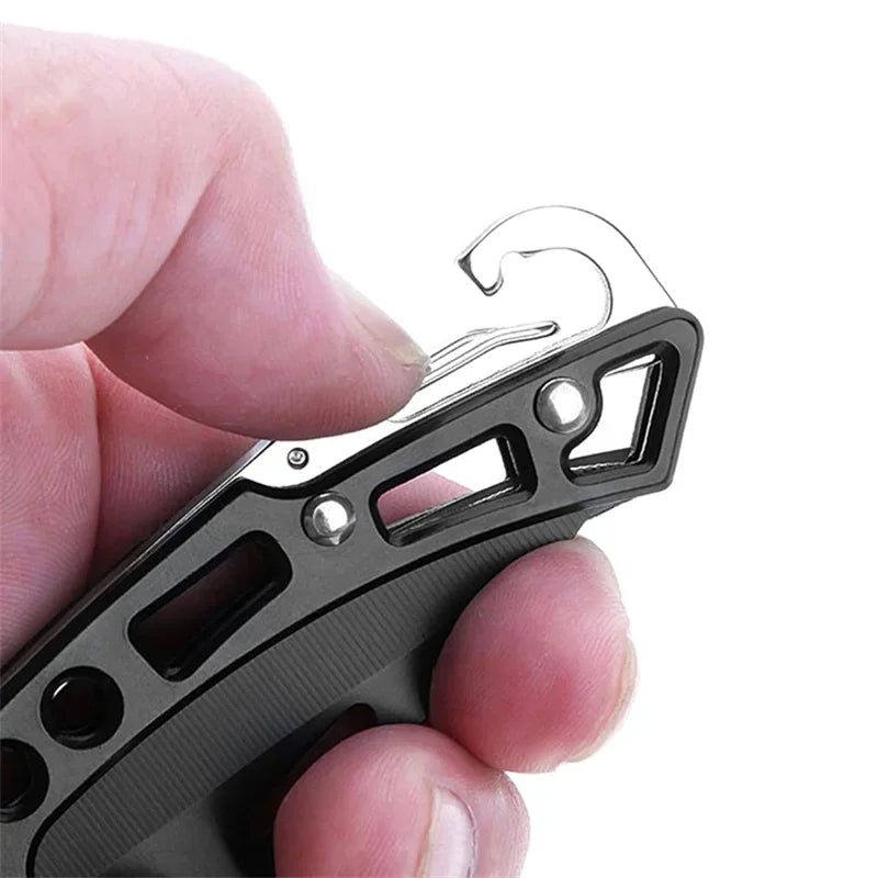 A hand holds a black folding stainless steel EDC pocket knife with a curved blade and serrated edge.