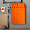 Orange silicone side burner rack and utensil storage mat hanging on a metal rack.
