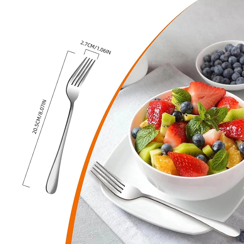 A stainless steel dinner fork is shown next to a bowl of fresh fruit and berries on a white plate.