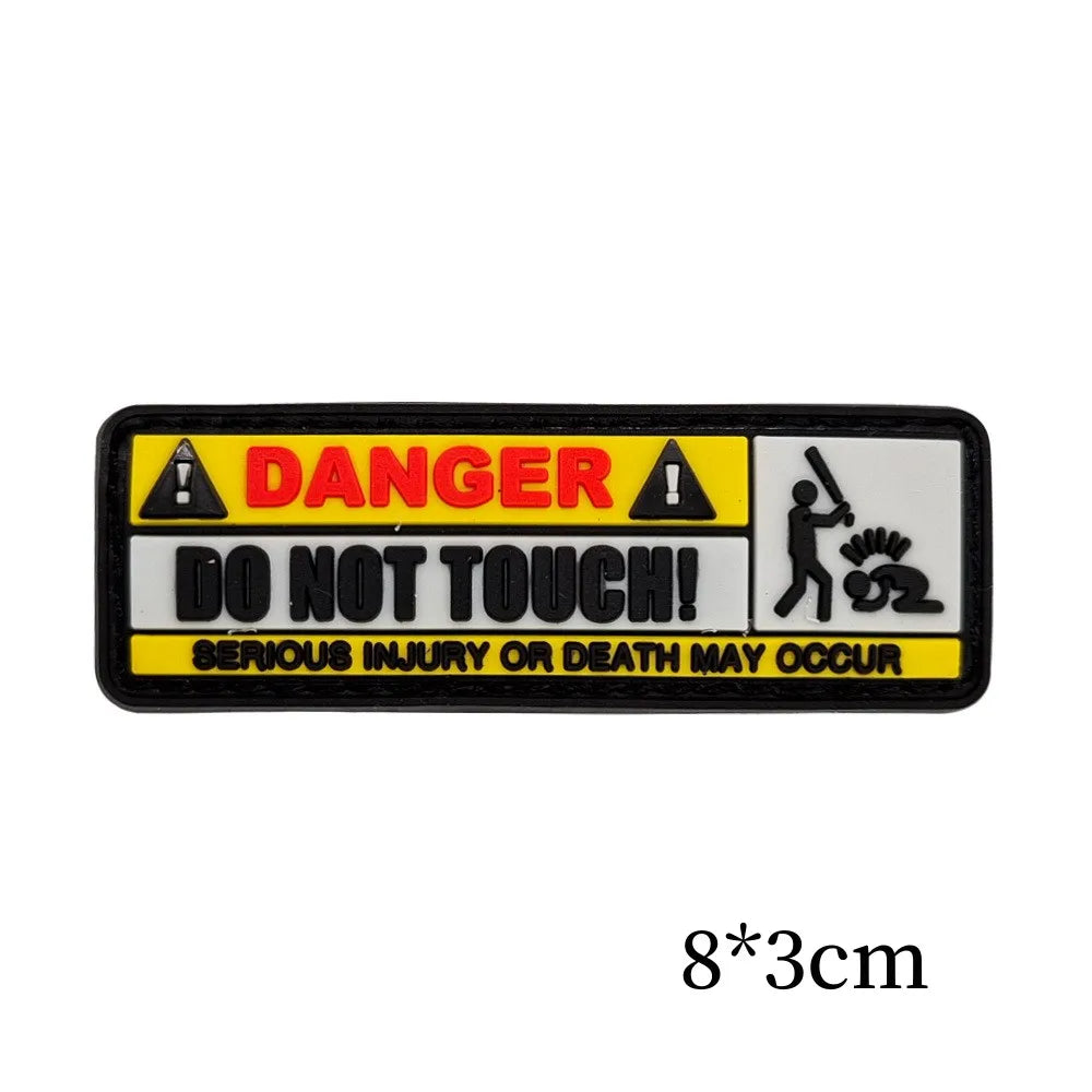 Black warning patch with yellow text and symbols indicating danger and a warning not to touch.